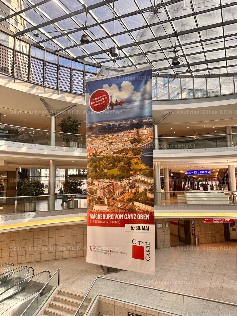 80_city-carre_8213 | Wenige Tage nach unserem Gespräch im City Carré war es so weit. Mitten im Einkaufscenter hing ein großes Plakat, das auf meine Luftbildausstellung aufmerksam machte. Ich blieb einen Moment stehen und betrachtete es. Vor gar nicht langer Zeit hatte ich meine Luftbilder einfach auf LinkedIn veröffentlicht – ohne einen konkreten Plan. Und nun wurden Besucher des City Carré mit einem großen Poster zu meiner Ausstellung eingeladen. Solche Augenblicke gehören zu den stillen Momenten des Stolzes. Nicht laut, nicht spektakulär, sondern einfach das gute Gefühl, dass sich Leidenschaft, Ausdauer und die Freude an der eigenen Arbeit auszahlen können. Diese Ausstellung entstand nicht durch Werbung oder Kaltakquise. Sie begann mit einigen Luftbildern auf LinkedIn und einem Menschen, der darin etwas Besonderes erkannte. Genau deshalb gehört auch dieses Foto zu meinen ganz persönlichen „Geschichten hinter der Kamera". Danke Herr Reuter - Realisiert mit Pictrs.com