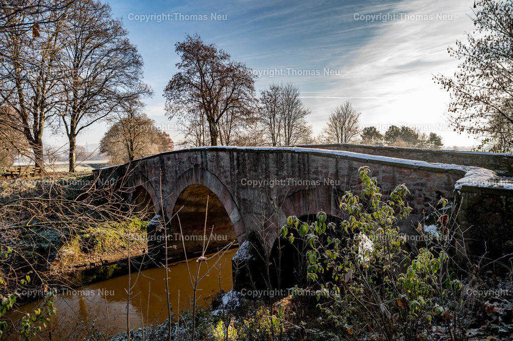 DSC_5078 | Im Winter entfaltet die Wattenheimer Brücke bei Lorsch eine besondere Atmosphäre. Das historische Bauwerk, das den Wattenheimer Bach überspannt, ist nicht nur ein Zeugnis alter Ingenieurskunst, sondern auch ein stiller Ort von landschaftlicher Schönheit. Eingebettet in die winterliche Umgebung nahe des UNESCO-Welterbes Kloster Lorsch, wirkt die Brücke unter Schnee und Raureif wie ein malerisches Relikt vergangener Zeiten.

Die Brücke erinnert an die lange Geschichte der Region: Als Teil alter Verbindungswege diente sie über Jahrhunderte hinweg Handel, Landwirtschaft und Pilgern. Heute ist sie ein beliebtes Fotomotiv und Ausflugsziel für Spaziergänge rund um Lorsch und das Ried.
