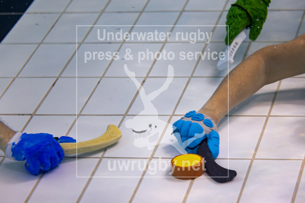 Unterwasser-Hockey: Rückrunde Liga 2023/2024 - Bild 13 | Symbolbild: Spiel-Puck mit  Schlägern und Spielerhänden. Der Hockey-Schläger wird in der jeweiligen Mannschaftsfarbe weiß oder schwarz gewählt. Ein Handschuh schützt die Hand eines Spielers vor Verletzungen durch den gegnerischen Schläger oder den Puck. - Realisiert mit Pictrs.com