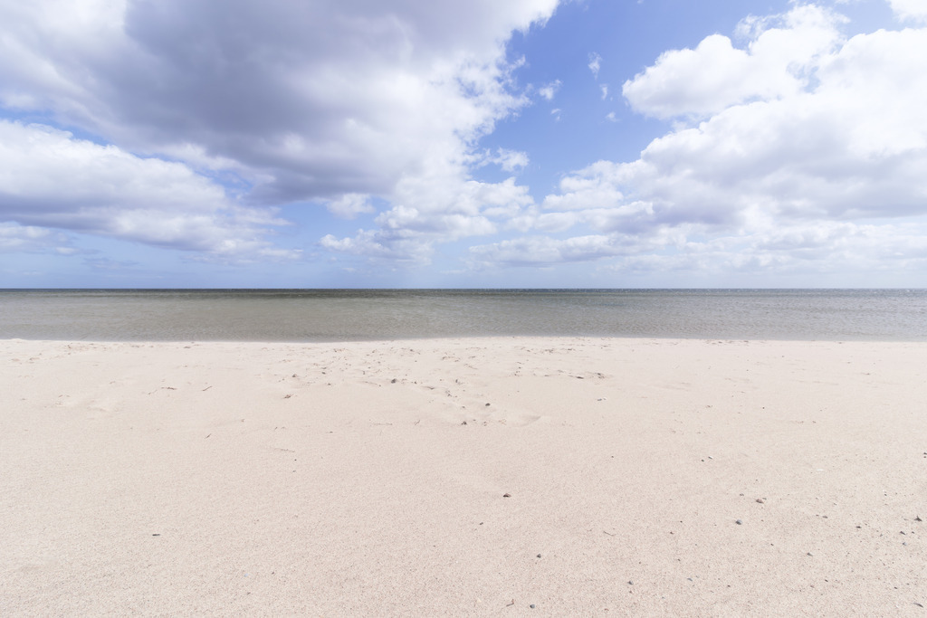Feiner Sandstrand unter weitem Himmel – Minimalistische Küstenfotografie | Ein heller Sandstrand, das ruhige Meer und ein weit geöffnetes Himmelsbild formen eine klare, minimalistische Küstenlandschaft voller Leichtigkeit. Die weichen Wolkenstrukturen und die sanfte Horizontlinie verleihen dem Motiv eine natürliche Eleganz, die den Blick entspannt und gleichzeitig fokussiert. Die reduzierte Komposition schafft eine Atmosphäre von Weite und Gelassenheit, die moderne Räume optisch öffnet und harmonisch ergänzt. Dieses Fine‑Art‑Wandbild wirkt besonders edel in puristischen Interiors und setzt einen hochwertigen, zeitlosen Akzent im gehobenen Wanddesign.