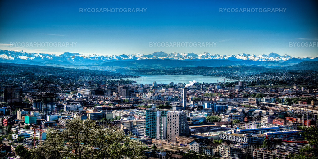 Zürich Panorama _ From City to Alps | Ein atemberaubender Panoramablick über die Stadt Zürich, aufgenommen an einem kristallklaren Tag, mit dem See und den majestätischen Schweizer Alpen, die den Horizont dominieren. Die perfekte Kombination aus urbanem Rhythmus und natürlicher Schönheit – das ideale künstlerische Foto für jedes Zuhause, Büro oder Geschäftslokal, das Ruhe, Weite und Schweizer Eleganz ausstrahlen möchte. - Realisiert mit Pictrs.com