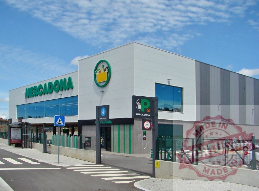 Mercadona supermarket building exterior with parking entrance | Mercadona grocery store exterior on a sunny day with cars entering the parking lot - Realized with Pictrs.com