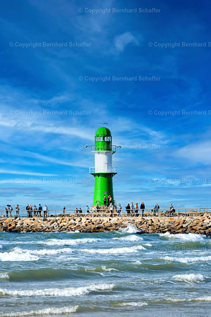 Leuchtturm Warnemünde | Leuchtturm an der Hafeneinfahrt von der Ostsee nach Warnemünde und Rostock mit Touristen auf der Promenade. - Realisiert mit Pictrs.com
