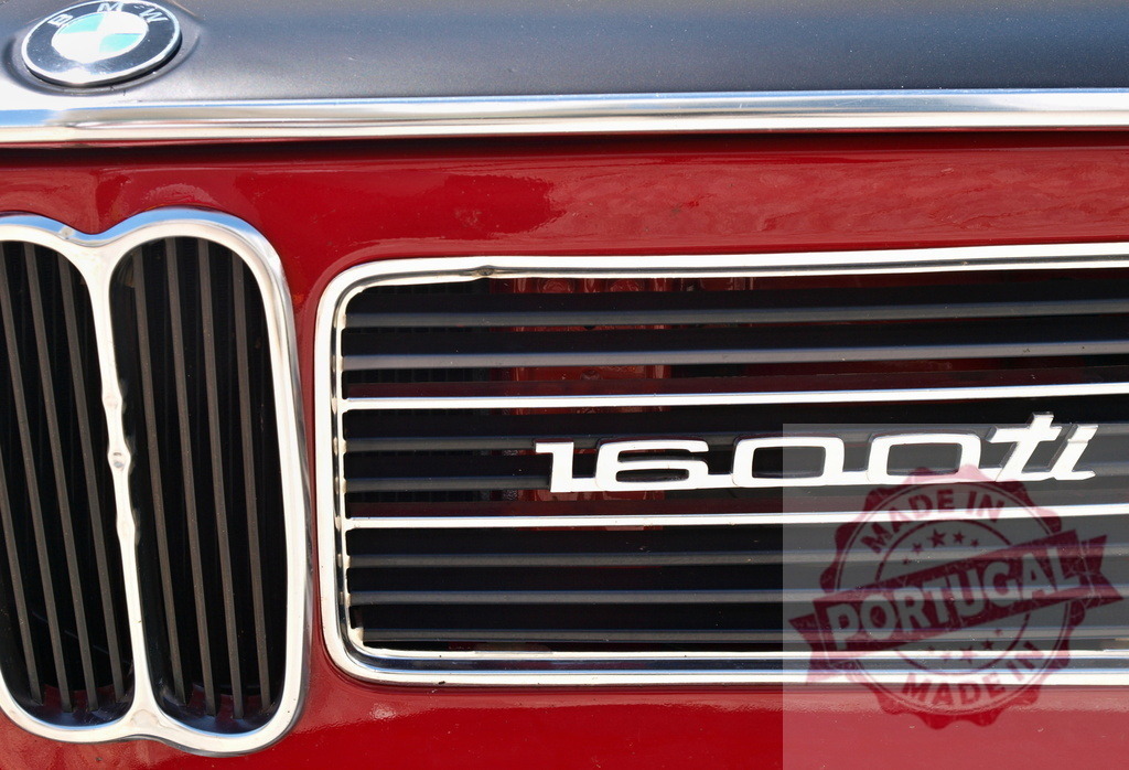 Close-up of BMW 1600ti logo on red vintage car | Shiny red vintage BMW 1600ti car featuring its logo on the front grill - Realisiert mit Pictrs.com