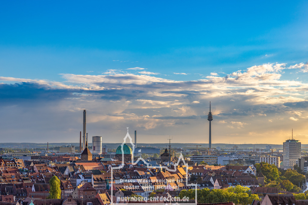 Monatsbild des Kalender 2025 für den Monat September | Panoramablick über die Stadt Nürnberg, mit markanten Gebäuden, darunter der Fernmeldeturm und das Heizkraftwerk Sandreuth im Hintergrund, das zur Einspeisung des Fernwaermennetzes genutzt wird. Der Himmel zeigt einige Wolken, die die Abendstimmung unterstreichen. - Realisiert mit Pictrs.com