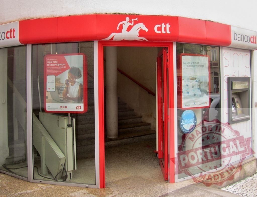 Banco CTT bank and post office entrance in Portugal | Banco CTT bank and post office storefront with ATM on a city street - Realized with Pictrs.com