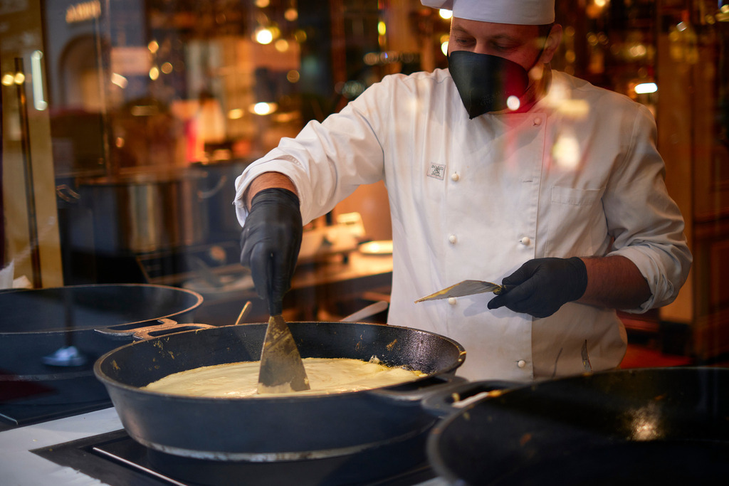 Kaiserschmarrenzubereitung in der Hofzuckerbäckerei Demel | Wien, Austria - November 22, 2021: K. u. K. Hofzuckerbäckerei Demel; Blick durch das Schaufenster auf die Zubereitung eines Kaiserschmarrens während dem Lockdown. - Realisiert mit Pictrs.com