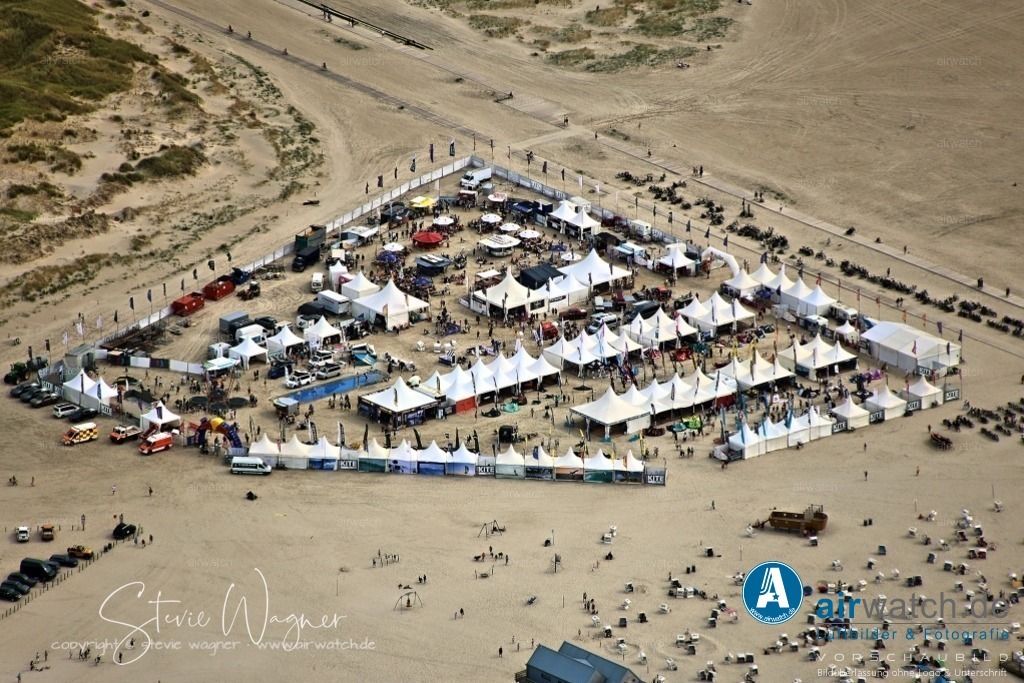 Luftbilder St.Peter-Ording - California Kitesurf Masters | Die California Kitesurf Masters finden vom 20. bis 24. August 2025 in St. Peter-Ording statt.An diesem Event treffen sich die besten Kitesurfer Deutschlands und es werden verschiedene Disziplinen wie Best Trick Freestyle und Big Air ausgetragen. Neben den Wettbewerben gibt es auch eine Kite-Expo, in der neuestes Equipment ausprobiert werden kann.Das Kite Village bietet Pop-Up Stores, Promotionstände und ein attraktives Rahmenprogramm für die ganze Familie.Abends verwandelt sich ein Teil des Festival-Geländes in ein Open-Air-Party-Areal mit DJs und Live-Auftritten.Die Veranstaltung findet im Nationalpark Wattenmeer statt, was eine besondere Verantwortung für Nachhaltigkeit und Naturschutz mit sich bringt.