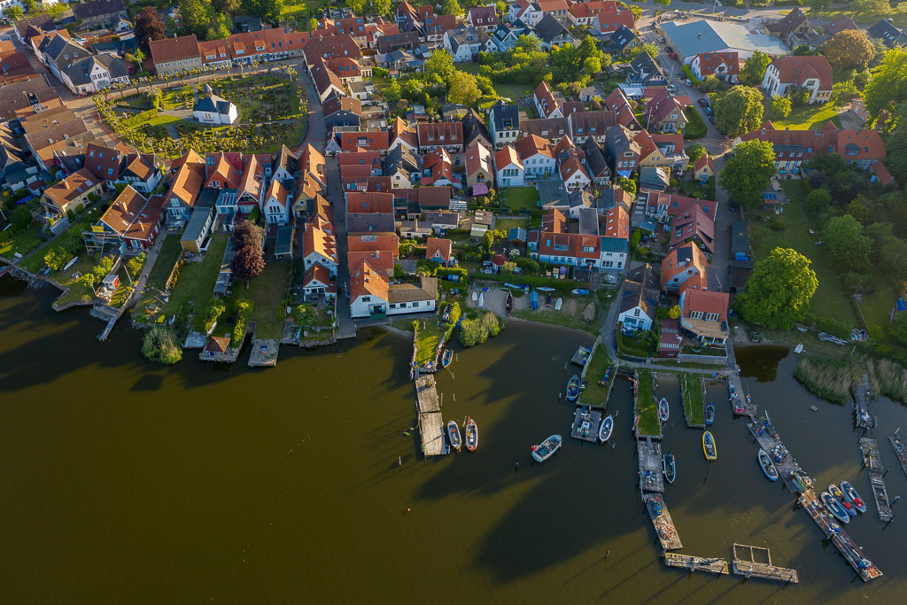 zeitenwende-farbe-01-01 | Luftaufnahme der Fischersiedlung Holm in Schleswig an der Schlei. Das Bild entstand kurz nach Sonnenaufgang. An den Brücken sind die offenen Motorboote der Holmer Fischer zu erkennen. - Realisiert mit Pictrs.com