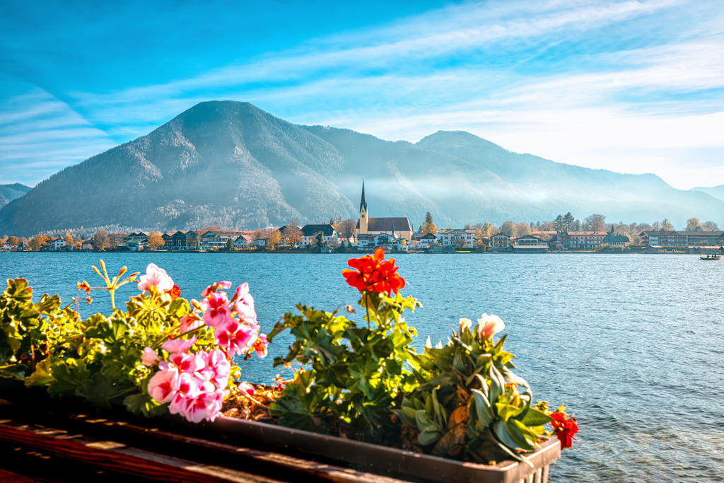 Malerischer Blick auf die Pfarrkirche St. Laurentius, im Hintergrund der Wallberg, Tegernsee | Das ausgewählte Foto zeigt den malerischen Tegernsee in Oberbayern mit Blick auf die Gemeinde Rottach-Egern und den markanten Turm der katholischen Pfarrkirche St. Laurentius.Details zum Zentral im Bild am Ufer sieht man die im Kern spätgotische und barockisierte Kirche im Ortsteil Egern. - Realisiert mit Pictrs.com