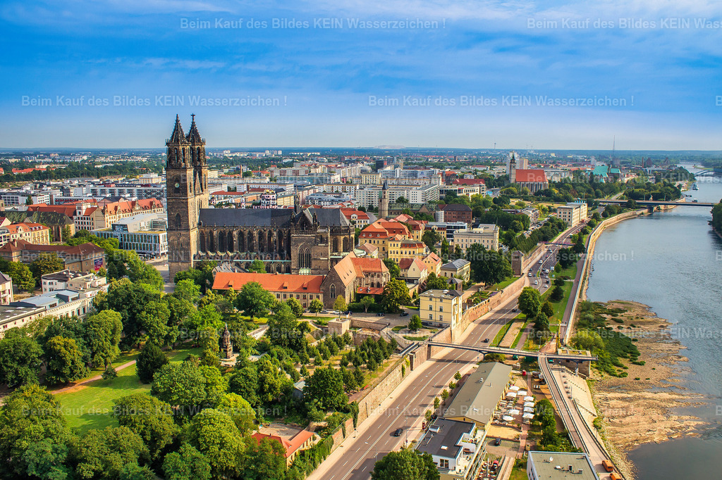 Luftbild-Magdeburg-Dom-Schleinufer-Fürstenwall-5166 | Der Fürstenwall gehört zu den wenigen Bereichen Magdeburgs, an denen sich die Geschichte der ehemaligen Stadtbefestigung noch besonders deutlich nachvollziehen lässt.Magdeburg war über Jahrhunderte eine stark befestigte Stadt. Die Elbseite wurde durch Mauern, Türme, Bastionen und vorgelagerte Festungsanlagen geschützt. Der Bereich am heutigen Fürstenwall war Teil dieser Befestigung und sicherte die Stadt unmittelbar an der Elbe.Im 18. Jahrhundert verlor die Festungsanlage zunehmend ihre militärische Bedeutung. Unter Fürst Leopold von Anhalt-Dessau wurden Teile der Befestigung ab 1708 zu einer repräsentativen Promenade umgestaltet. Aus dem militärischen Wall entstand der heutige Fürstenwall – einer der ältesten erhaltenen Promenadenbereiche Magdeburgs.Noch heute lassen sich entlang des Fürstenwalls Abschnitte der historischen Festungsanlagen erkennen. Der Wall verbindet damit auf besondere Weise Magdeburgs Militärgeschichte mit dem heutigen innerstädtischen Grünraum.Der Magdeburger Dom steht unmittelbar dahinter und macht sichtbar, wie eng sich an diesem Ort mehrere Jahrhunderte Stadtgeschichte überlagern: mittelalterliche Stadt, Festungsstadt und heutige Innenstadt.Ein Ort, an dem Magdeburgs Geschichte nicht nur in Büchern, sondern noch heute im Stadtgrundriss sichtbar ist. - Realisiert mit Pictrs.com