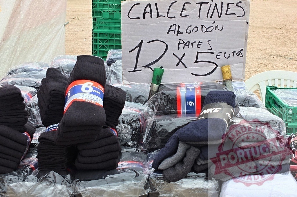 Street market display of cotton socks with handwritten price sign | Cotton socks neatly stacked at an outdoor market with a price sign displayed - Realized with Pictrs.com
