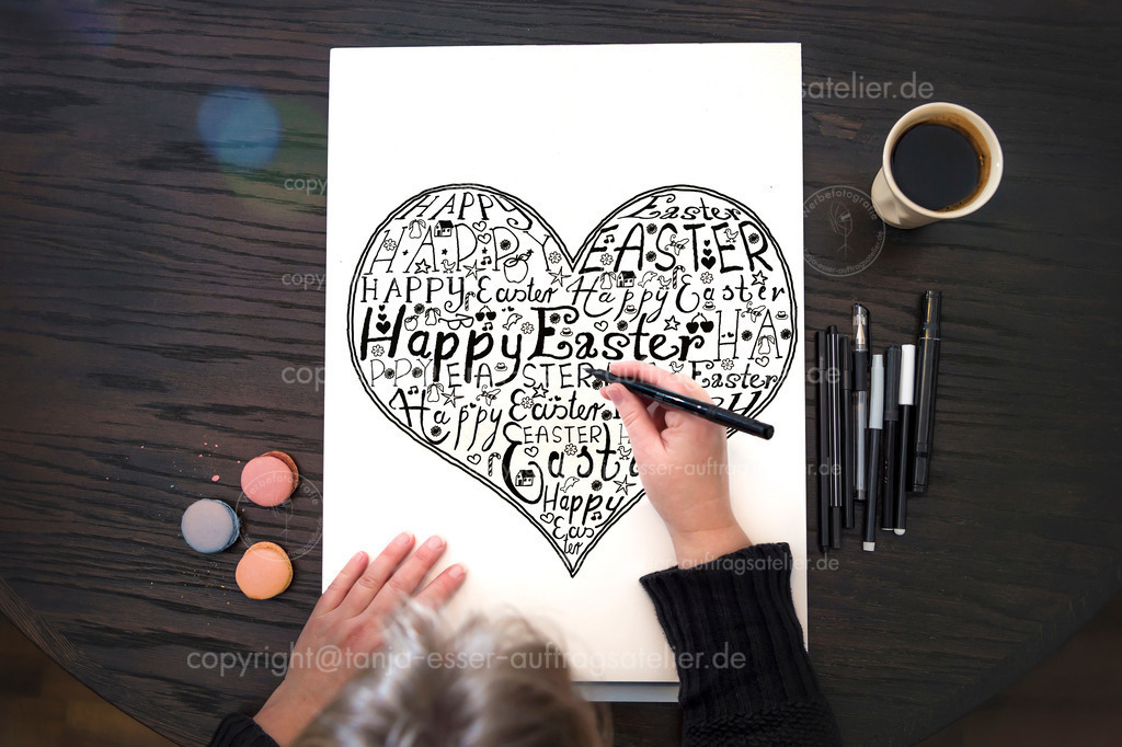 Hand lettering - A woman sits at the table and draws the text Happy Easter on paper | Hand Lettering - Eine Frau sitzt am Tisch und zeichnet den Text Frohe Ostern auf Papier