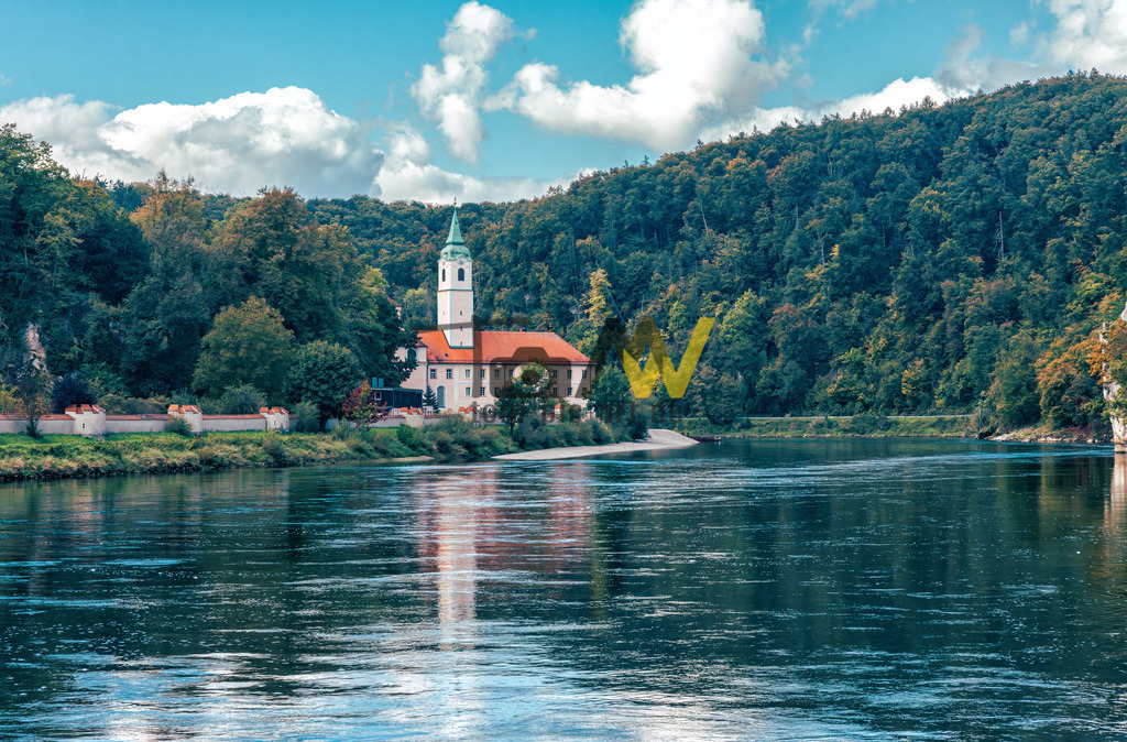 Das Kloster Weltenburg an der Donau, schöne Spiegelung im stillen Fluss | Das Bild zeigt das Kloster Weltenburg, ein berühmtes Benediktinerkloster in Bayern, das für seine malerische Lage am Donaudurchbruch bekannt ist. Das Kloster liegt direkt am Eingang der "Weltenburger Enge", einem Naturschutzgebiet, das vom Europarat mit dem "Europadiplom" ausgezeichnet wurde. Es gilt als eine der ältesten Abteien Bayerns, die Ursprünge reichen bis ins Jahr 617 zurück. Die Klosterbrauerei, gegründet im Jahr 1050, beansprucht den Titel der ältesten Klosterbrauerei der Welt und ist besonders für ihr dunkles Bier bekannt. Die beeindruckende Abteikirche St. Georg wurde von Cosmas Damian Asam im Stil des süddeutschen Rokoko erbaut.  - Realisiert mit Pictrs.com