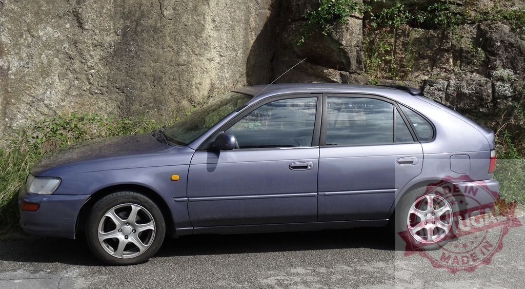 Toyota Corolla hatchback car parking beside rock wall | Purple Toyota Corolla hatchback parked on asphalt road next to ancient rock wall - Realisiert mit Pictrs.com