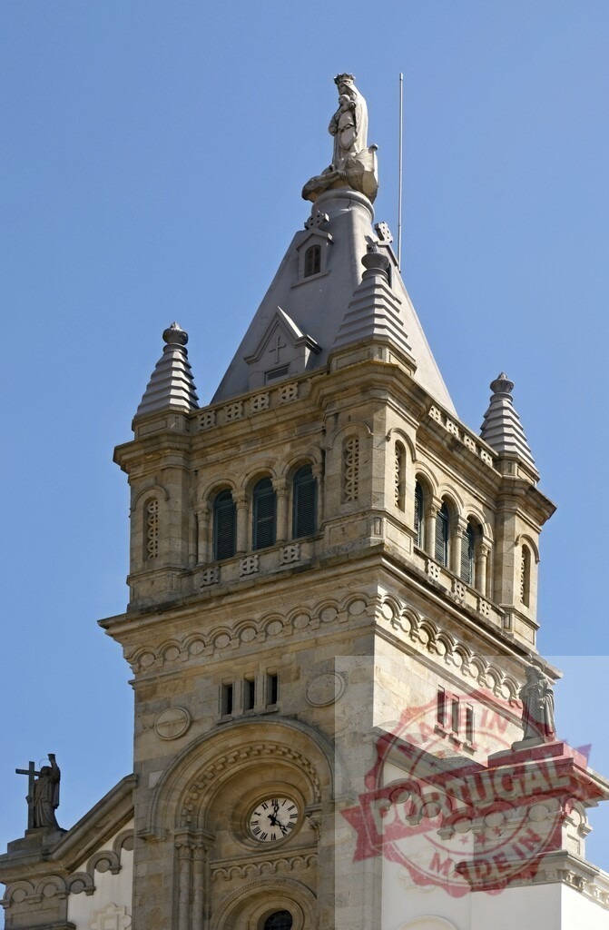 Church tower with Virgin Mary statue and clock | Stone church tower reaching blue sky, featuring a Virgin Mary statue and a clock - Realized with Pictrs.com
