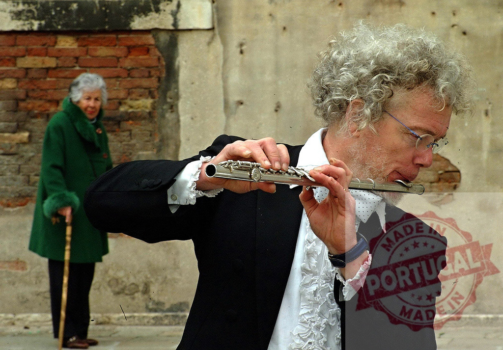Musician playing flute in Venice with elderly woman walking by | Street musician playing a transverse flute in Venice, Italy, with an elderly woman walking in the background - Realisiert mit Pictrs.com