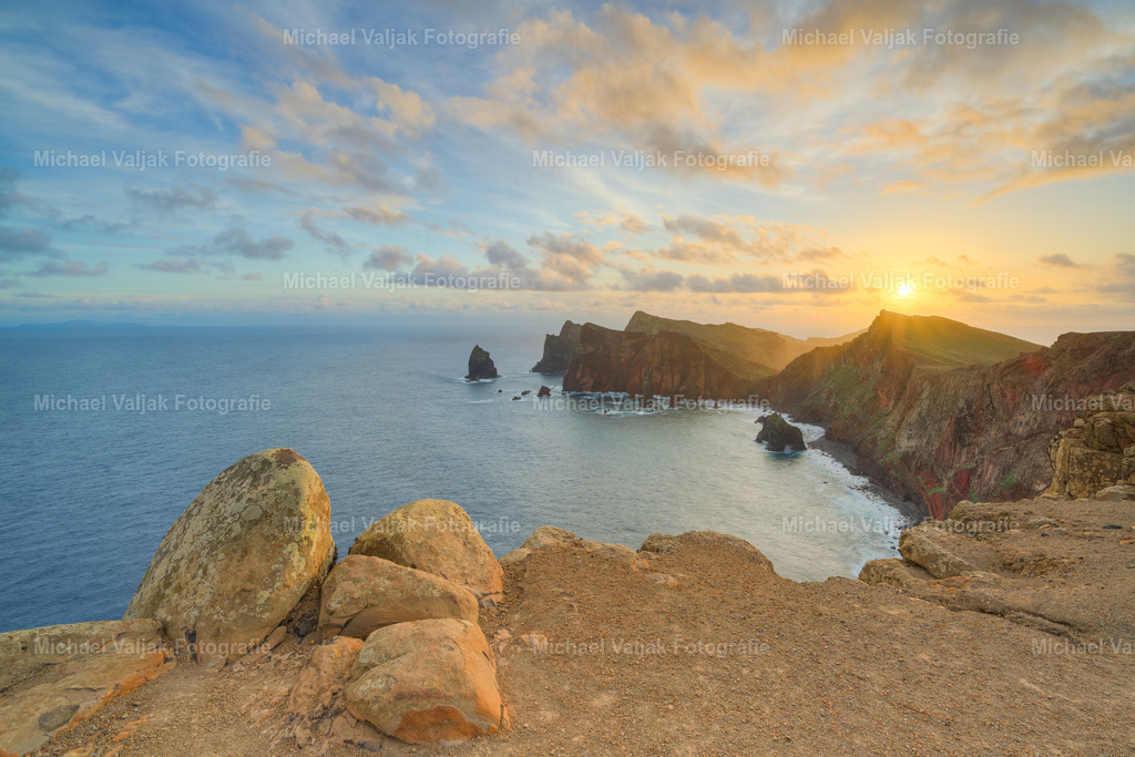 Miradouro da Ponta do Rosto bei Sonnenaufgang | Der Blick vom Miradouro da Ponta do Rosto über einen Teil der Halbinsel Ponta de São Lourenço auf Madeira ist besonders bei Sonnenaufgang ein unvergessliches Erlebnis. Die ersten Strahlen der Sonne malen den Himmel in zarte Gelb- und Orangetöne, während die Klippen der Ostküste dramatisch aus dem Atlantik ragen. Die Stille des frühen Morgens wird nur vom leisen Rauschen der Wellen und dem Rufen der Seevögel begleitet, was diesem Ort eine magische Atmosphäre verleiht. - Realisiert mit Pictrs.com