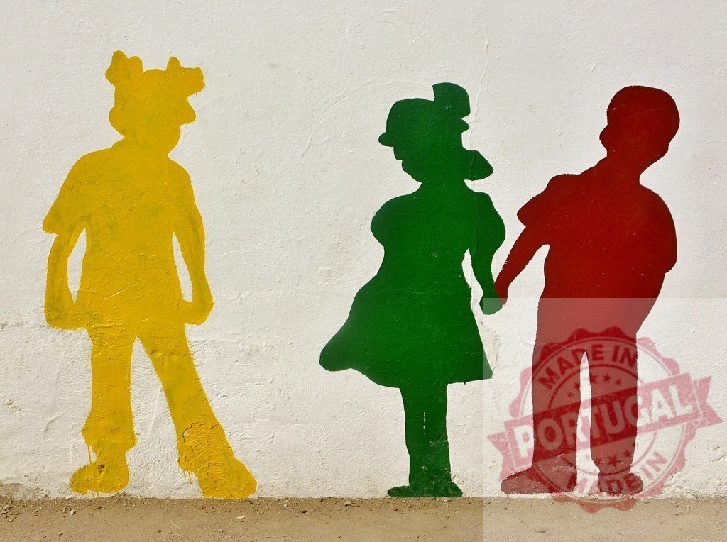 Children silhouettes mural showing exclusion and connection | Three colorful child silhouettes on a wall, two holding hands and one standing apart - Realized with Pictrs.com