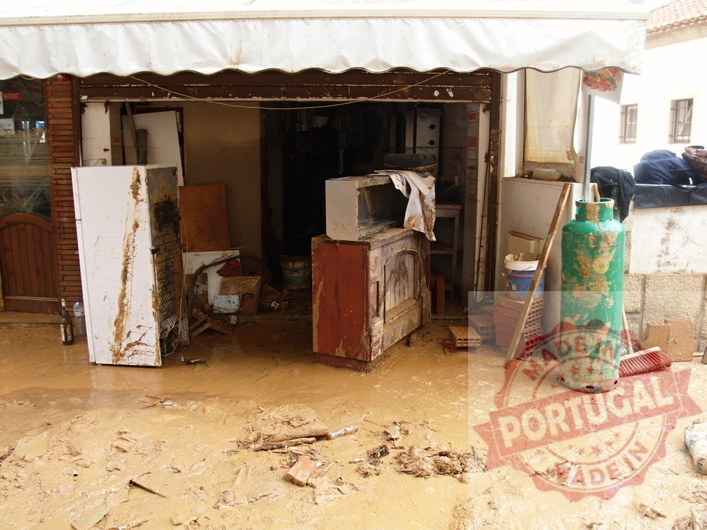 Mud and debris filling a business entrance after severe flood | Albufeira Flood - discruction by weather problems Storefront filled with mud and damaged items following a devastating natural disaster - Realisiert mit Pictrs.com