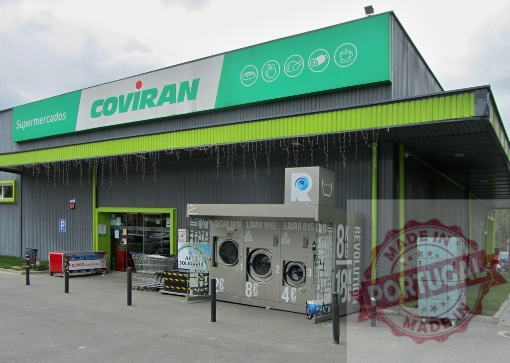 Coviran supermarket building with outdoor self-service laundry machines | Coviran supermarket exterior featuring a self-service coin-operated laundry machine and shopping carts - Realisiert mit Pictrs.com