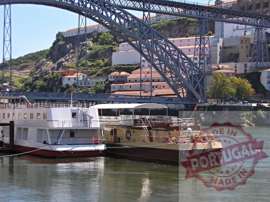 Luís I Bridge spanning Douro River in Porto, Portugal. Porto - Portugal | Douro river cruise boats docked on a sunny summer day in Porto cityscape - Realized with Pictrs.com