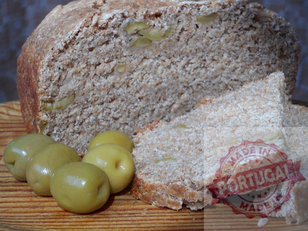 Artisan olive bread loaf with fresh green olives | Hearty sourdough olive bread with slices and whole green olives on a rustic wooden board - Realisiert mit Pictrs.com