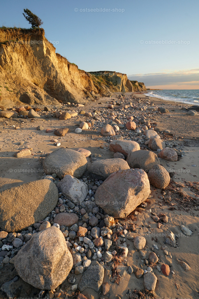 Findlinge im Abendsonnenlicht | Findlinge liegen in der Abendsonne am Strand und werfen lange Schatten auf den Sand.