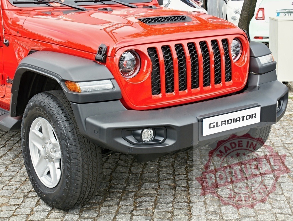 Red Jeep Gladiator pickup truck parked on cobblestone street | Red Jeep Gladiator pickup truck showcasing front grille, bumper, and tire on cobblestone - Realisiert mit Pictrs.com