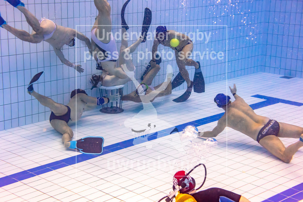 Unterwasser-Rugby 5. Spieltag 1. Bundesliga Süd (Saison 2023/24) | Spiel STC München (weiß) gegen Tauchclub Bamberg (blau). Bamberg im Aufbau des Spielangriffs auf das Malscher Tor, Veit Hofmann (blau #1) passt auf Lukas Tadda (blau #4) in der Mitte, der links unter dem Korb Sebastian Lange (blau #11) als Anspielposition sieht. - Realisiert mit Pictrs.com