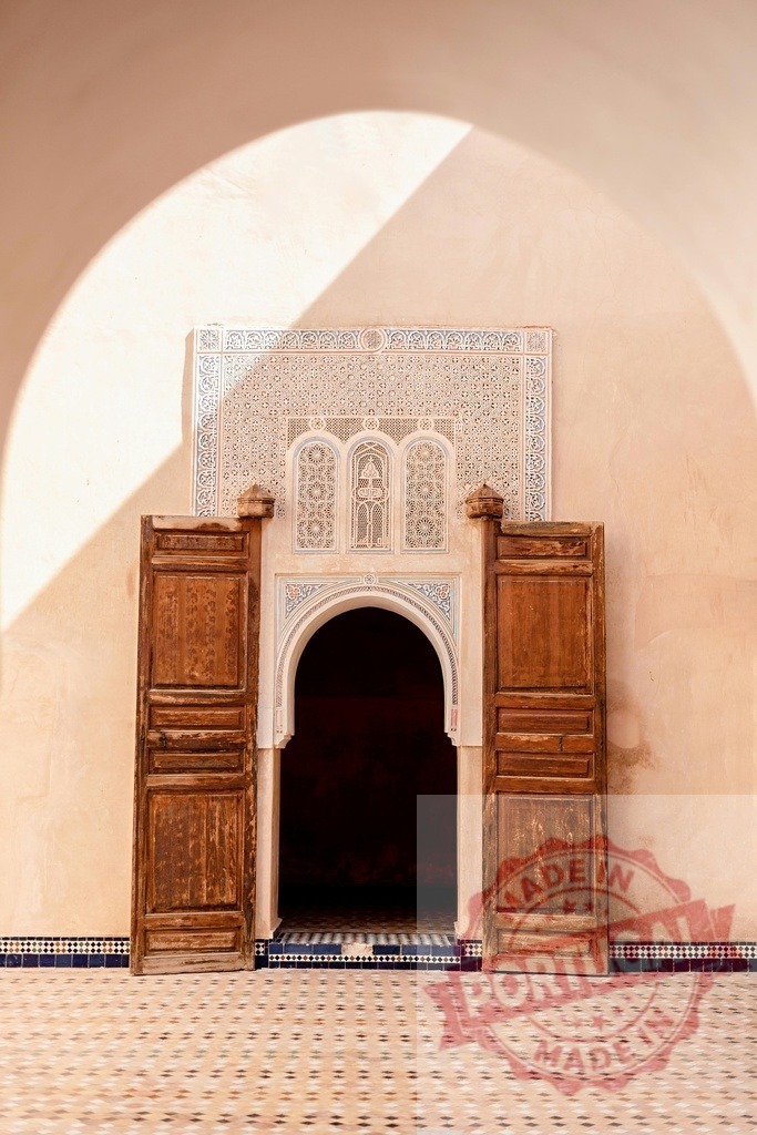 Moroccan arch door with Islamic arabesque tilework and sunlight shadow | Ornate archway with open wooden door and intricate Islamic tile designs in a sunny courtyard - Realisiert mit Pictrs.com