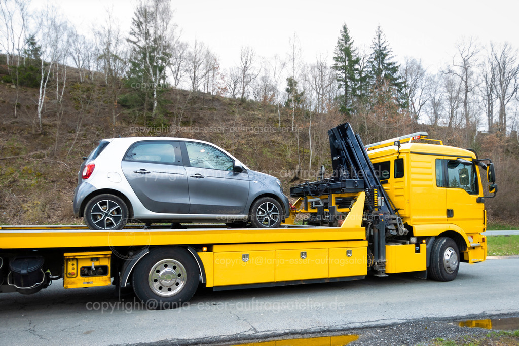 E Auto wird abgeschleppt D | Ein kleines Elektro Auto wird vom Pannendienst verladen. Es ist auf einem Parkplatz neben einer Landstraße stehen geblieben, weil der Akku leer ist und es keine E Ladestation in der Nähe gibt. 
