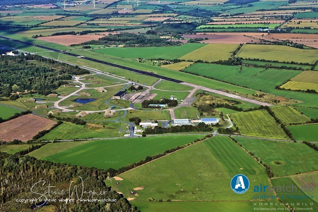 Luftbild Flughafen Husum-Schwesing - Der Flugplatz entstand aus Teilen des ehemaligen militärischen Fliegerhorsts Husum | Der Flugplatz wird von der Flughafen Husum GmbH & Co. KG betrieben und ist Basis für Versorgungs- und Wartungsflüge zu Windparks und Umspannplattformen auf der Nordsee sowie zur Forschungsplattform FINO 3. - Der Flugplatz entstand aus Teilen des ehemaligen militärischen Fliegerhorsts Husum und wurde im Mai 2000 für den zivilen Betrieb eröffnet. - Luftbild Position: Queranflug Piste 03 -