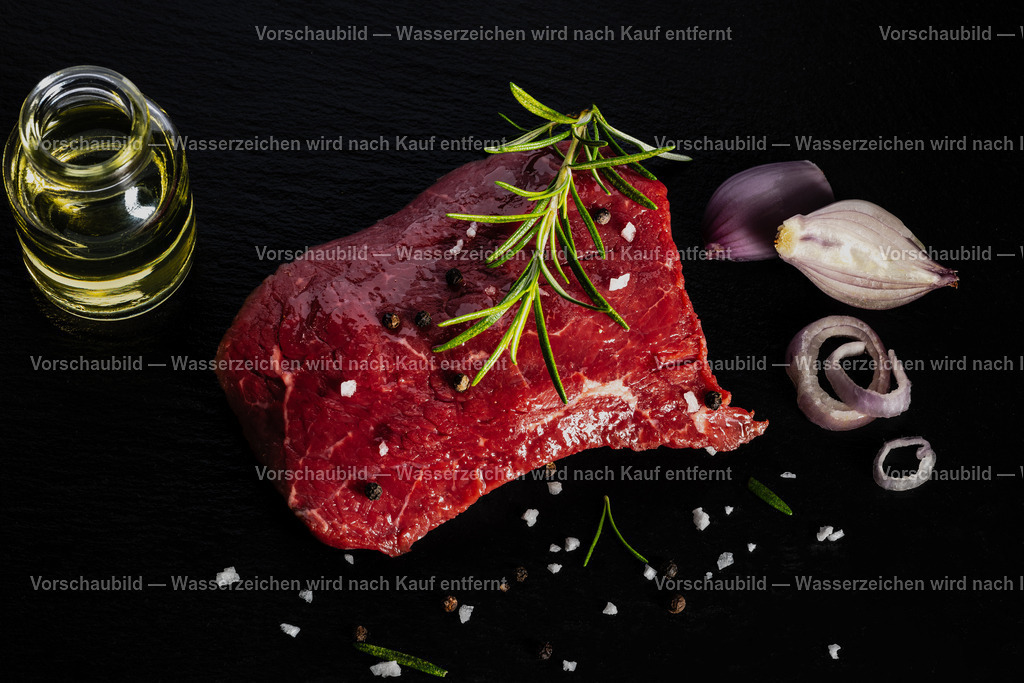 rohes Rinder Hüftsteak auf schwarzer Schieferplatte angerichtet | rohes Rinder Hüftsteak auf schwarzer Schieferplatte angerichtet. Dekoriert mt einen Zweig Rosmarien, Pfefferkörnern, Schalotten, Öl und groben Salz - Realisiert mit Pictrs.com