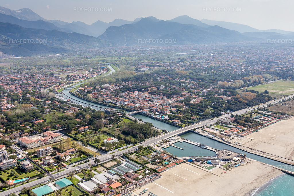 Aerial view: River mouth on the coast of the Ligurian Sea in front of the alpine mountain scenery of Massa in Capanne-Prato-Cinquale in the district Capanne-Prato-Cinquale in Montignoso in the state Massa-Carrara, Italy. – Photo: IMG_087201.jpg taken on 04/04/2016 by Werner Riehm/FLY-FOTO.com – Resolution of the original: 5472 x 3648 px