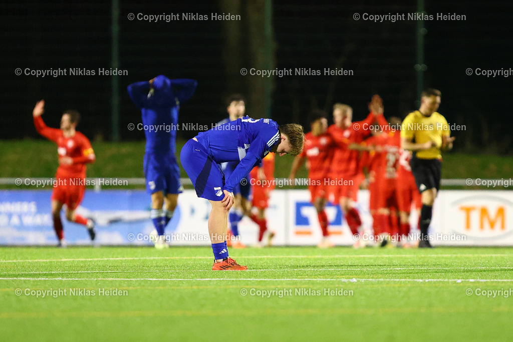NH_FCKiliaKiel_TuSRotenhof_FlensOberliga_18032026 | #18 Henry Grothkopp (TuS Rotenhof) schaut auf den Boden. Im Hintergrund bejubelt der FC Kilia Kiel den Sieg.Fußball I Herren I Flens Oberliga I Saison 2025-2026 I 18. Spieltag I FC Kilia Kiel - TuS Rotenhof I 18.03.2026 I Kilia Stadion