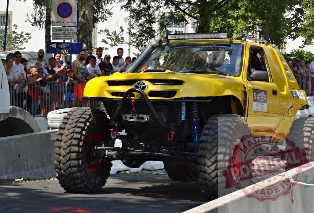 Yellow Toyota 4x4 competing in an urban off-road competition | Powerful yellow Toyota truck conquering obstacles in urban off-road race, captivating spectators - Realized with Pictrs.com
