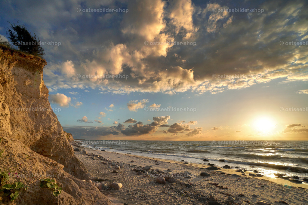 Magie des Moments | Das Bild zeigt einen Sonnenuntergang mit einem faszinierenden Abendhimmel über der Ostsee. Im Vordergrund werden Steilküste und Strand in ein warmes Licht gehüllt.