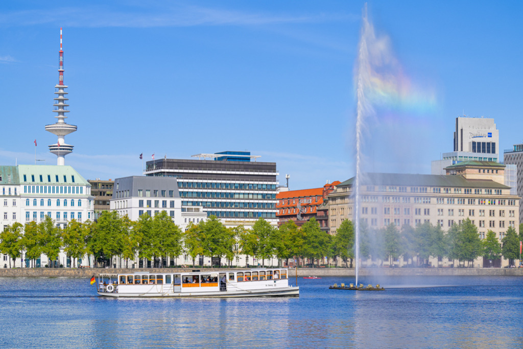 Alsterrundfahrt mit der St. Georg | Das historische Dampfschiff St. Georg (Baujahr 1876) bei einer Fahrt auf der Binnenalster in Hamburg. Die Ansicht zeigt die Westseite der Binnenalster bei strahlendem Sonnenschein; über der bis zu 60 Meter hohen Alsterfontäne hat sich ein Regenbogen gebildet. — Auflösung des Originals: 8256 x 5504 px. - Realisiert mit Pictrs.com