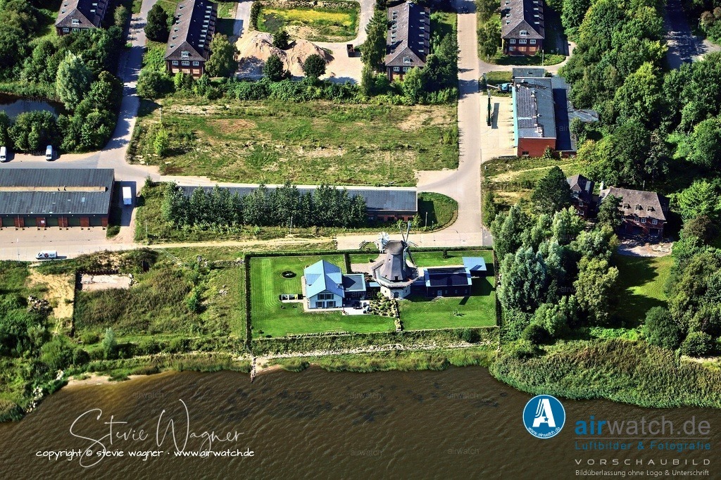 Luftbild Mühle Nicola in Schleswig | Im 18. Jahrhundert setzten sich die stabilere und leistungsfähigere Holländermühle aus den Niederlanden durch, die durch ihre drehbare Kappe und die Königswelle eine höhere Effizienz ermöglichte. Diese Mühlen wurden in verschiedenen Typen gebaut, darunter Erdholländer, Kellerholländer und Galerieholländer, wobei die letzteren besonders in dicht bebauten Gebieten aufgrund ihrer höheren Bauweise bevorzugt wurden.