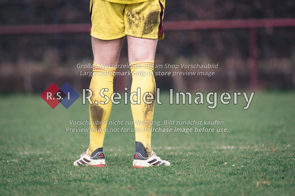 RS-1-035656 | Torwart in Adidas-Schuhen, gelbem Trikot und Stutzen mit Erdflecken steht auf Rasenplatz