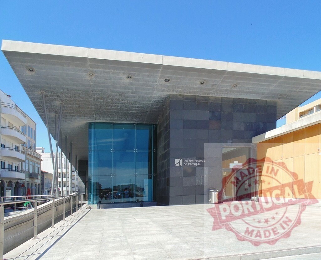 Viana do Castelo railway station modern architecture under sunny sky. Aveiro - Portugal | Viana do Castelo railway station facade featuring glass, stone, and a large concrete canopy - Realized with Pictrs.com