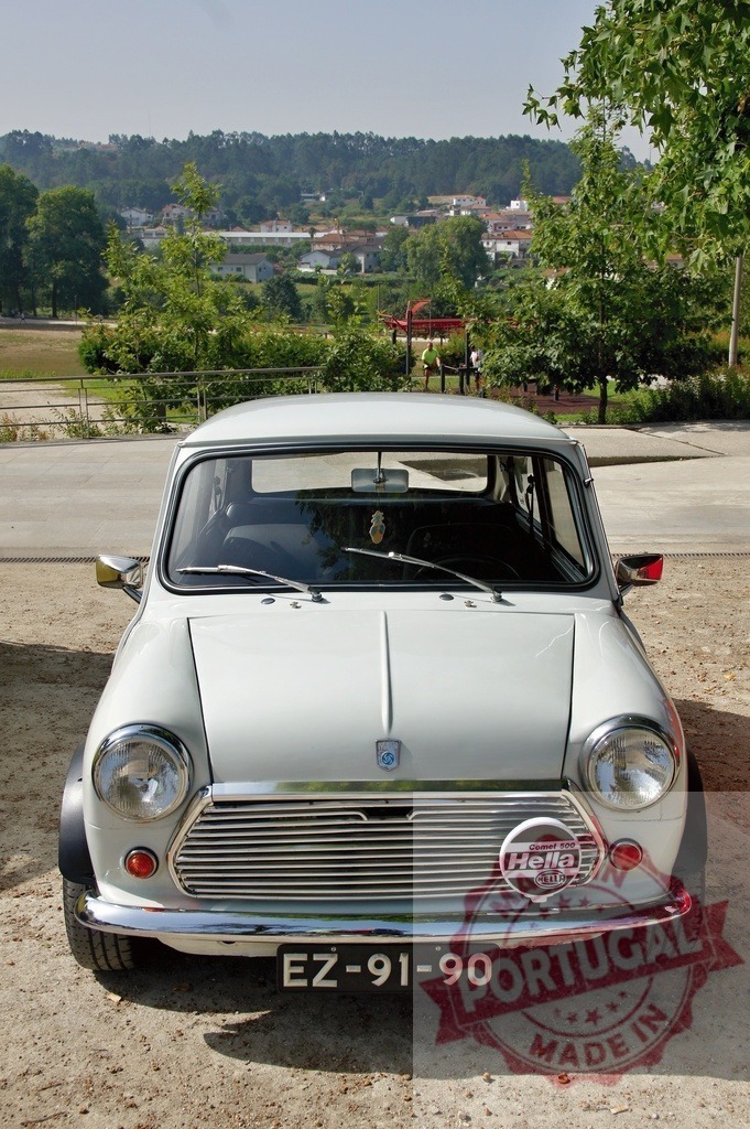 Classic Mini Cooper car parked in a rural landscape | White Classic Mini Cooper car parked near a park with a rural landscape in the background - Realized with Pictrs.com