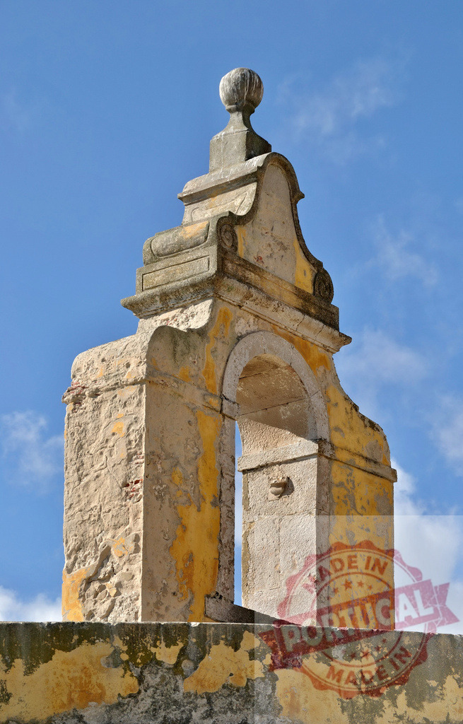 Weathered bell tower facade of ancient ruin against blue sky. Centro - Portugal | Historic bell tower architecture showing peeling paint and stone texture under a clear sky - Realized with Pictrs.com