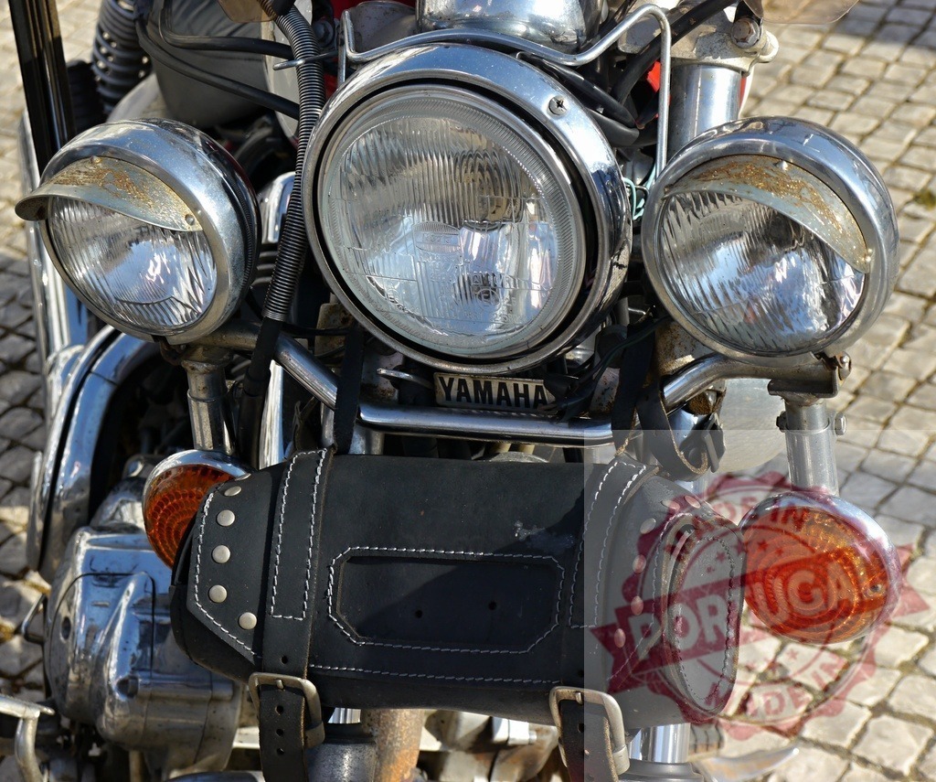 Yamaha motorcycle front detail showing headlights and tool bag | Yamaha motorcycle's chrome headlights and black leather tool bag creating a vintage aesthetic - Realized with Pictrs.com