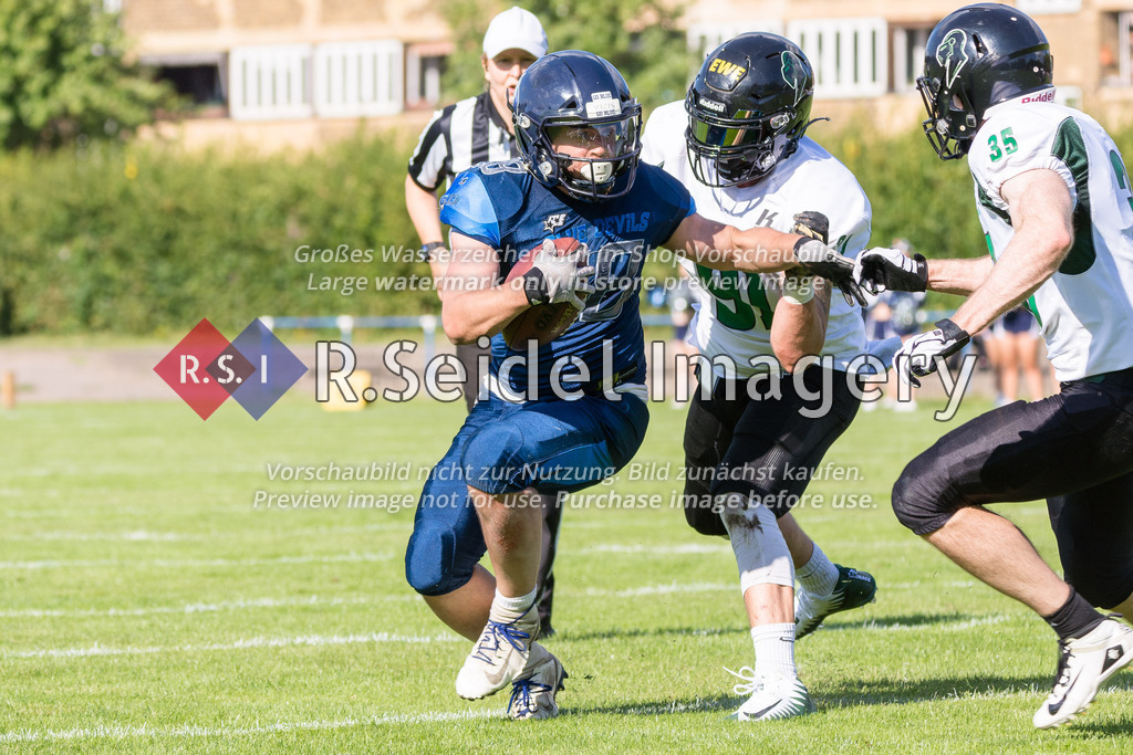American Football, Saison 2022, Regionalliga Nord, Hamburg Blue Devils - Oldenburg Knights, Dr.-Hermann-Schnell-Sportplatz (Hamburg), 06.08.2022, 07. Gameweek | Marius Fiedler (#28, Blue Devils, RB) weicht Jannik Birk (#91, Oldenburg, LB) und Felix Marterer (#35, Oldenburg, LB) aus.