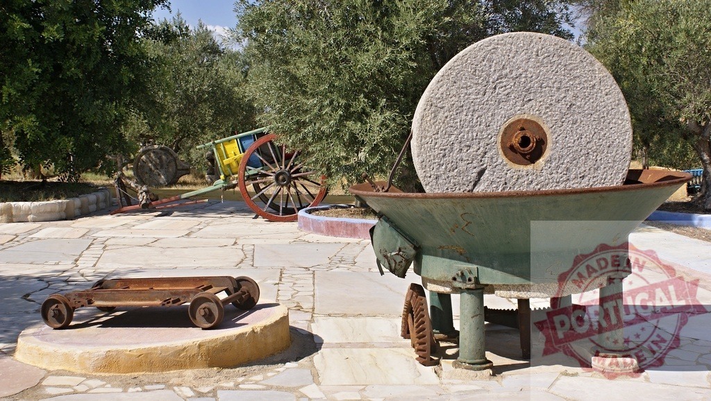 Traditional olive oil millstone crushing olives | Old millstone and olive press machinery standing in a rural farm yard - Realized with Pictrs.com