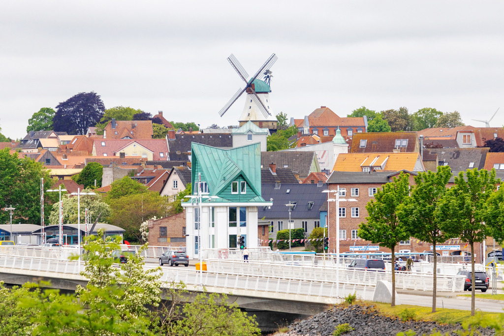 Wandbild: Schleibrücke und Windmühle in Kappeln | Dieses Wandbild im Querformat zeigt die Schleibrücke sowie die Windmühle in Kappeln im Frühling. Der Himmel ist bewölkt.  - Realisiert mit Pictrs.com