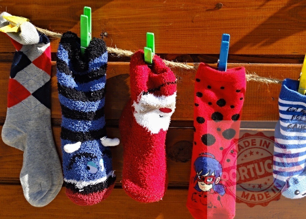 Colorful socks hanging and drying on clothesline with clothespins | Funny socks with Santa Claus and Ladybug prints are drying on a clothesline - Realisiert mit Pictrs.com