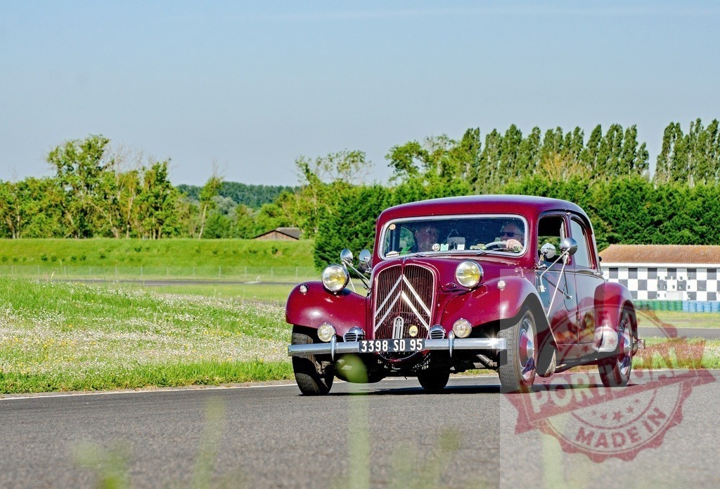 Citroën Traction Avant vintage car driving on road | Red Citroën Traction Avant classic car driving on a rural road during a sunny day - Realized with Pictrs.com